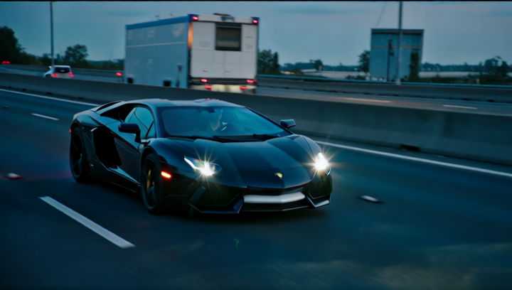 A black sports car speeds down the highway, its headlights cutting through th...