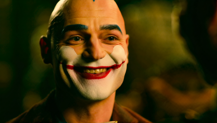 A skinny joker smiles with a wide grin as blood runs down the corners of his ...