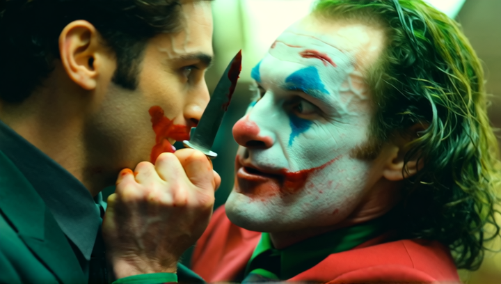 A bank manager is terrified as the Joker laughs and holds a knife up to the m...